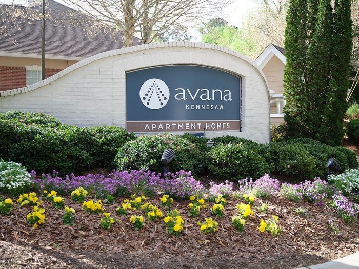 Inviting apartment entrance featuring vibrant landscaping and stylish signage at Avana Kennesaw.