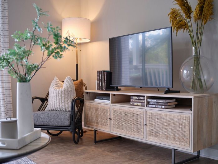 Chic living room with a modern TV stand, cozy armchair, warm lighting, and stylish decor, creating an inviting atmosphere.