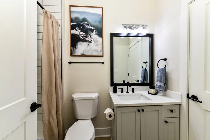 Chic bathroom design featuring a sleek vanity with black fixtures, elegant lighting, and an inviting shower space.