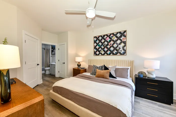Bright and cozy bedroom with modern decor, featuring a plush bed, stylish artwork, and warm lighting for a welcoming atmosphere.