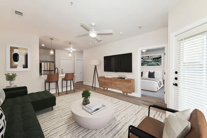 Modern open-concept living area with stylish decor, featuring a cozy seating arrangement, elegant artwork, and a sleek kitchen bar with pendant lighting.