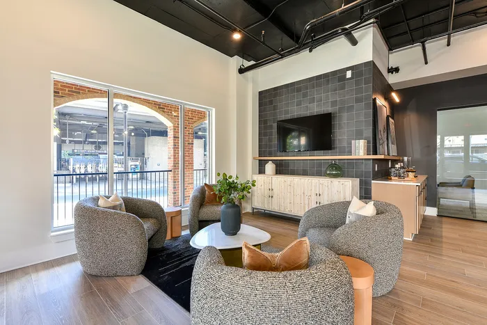 Modern apartment lounge area with plush seating, stylish decor, and large windows offering ample natural light.