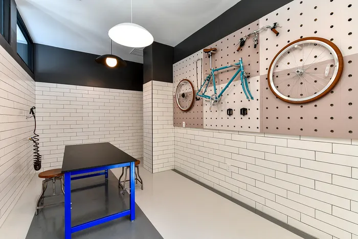 Sleek apartment amenity showcasing a modern bike repair station with vibrant blue workbench and organized wall-mounted bike tools.