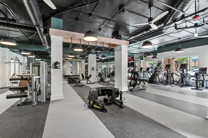 Modern fitness center equipped with state-of-the-art machines, including treadmills, weight benches, and stationary bikes, under stylish industrial lighting.