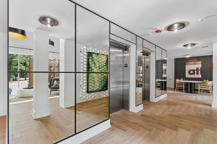 Modern apartment lobby showcasing sleek elevators, elegant wood flooring, and inviting seating area with stylish decor.
