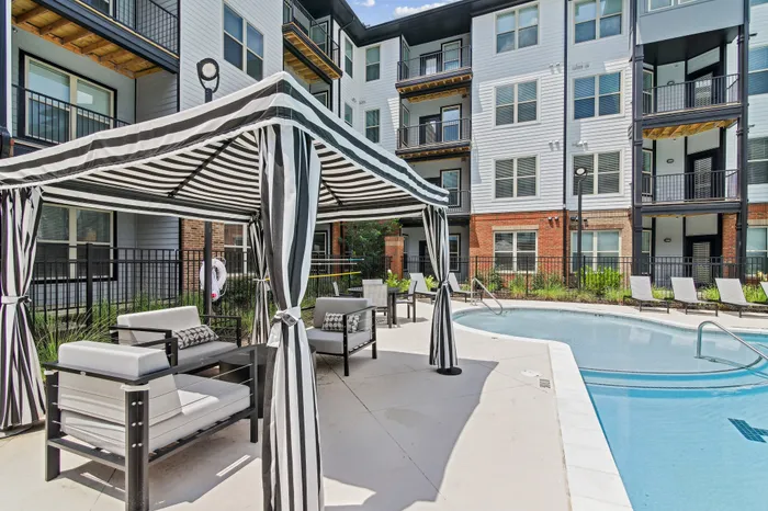 Luxurious apartment exterior featuring a modern poolside lounge with stylish cabanas and comfortable seating.