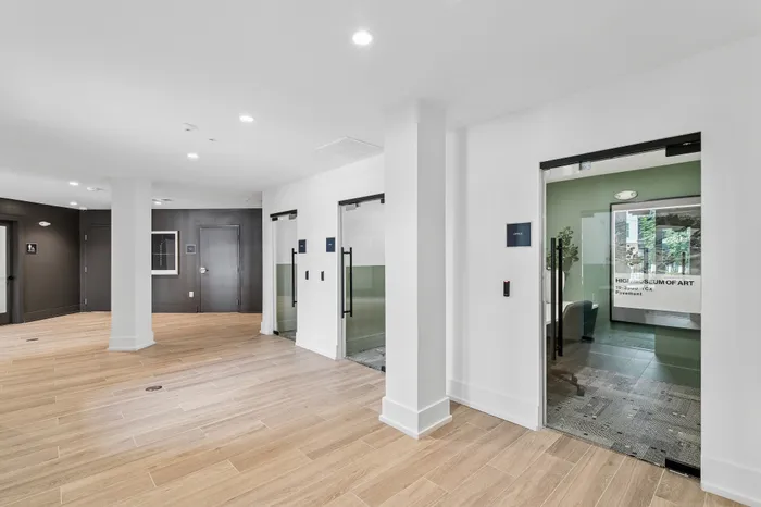 Bright and modern lobby with sleek wood flooring, glass door entries, and contemporary design elements offering a welcoming atmosphere.