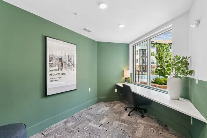 Bright and modern study nook featuring a sleek desk, comfortable chair, and a large window with a view of lush greenery.