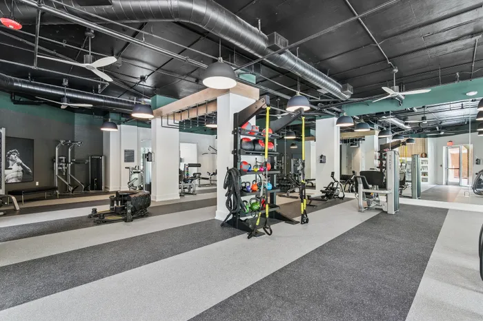 Spacious and modern gym with top-of-the-line equipment, vibrant decor, and ample lighting for an energizing workout experience.