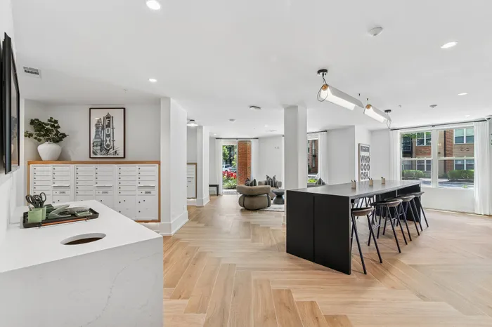 Bright, modern community area with stylish seating, long communal table, and large windows offering garden views.