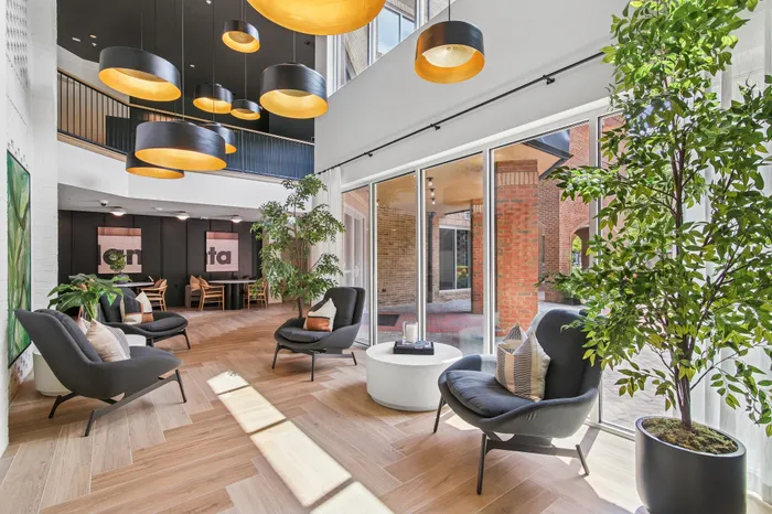Luxurious modern living area featuring floor-to-ceiling windows, stylish lounge chairs, lush greenery, and contemporary lighting.