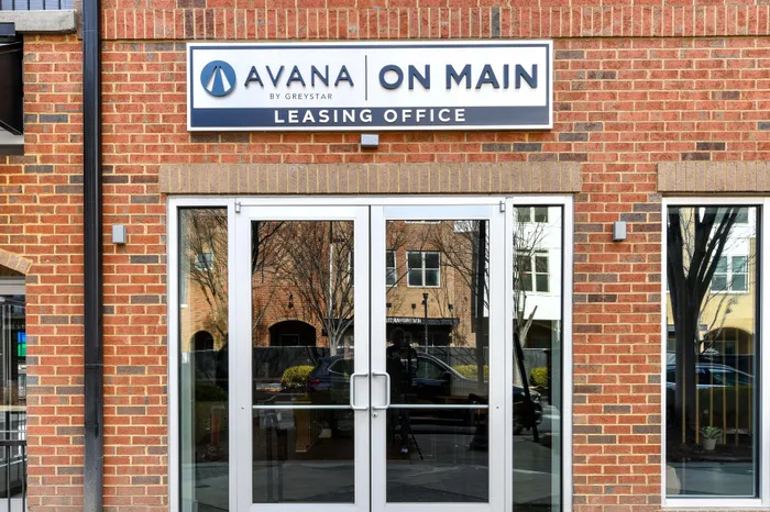 Inviting entry to Avana on Main leasing office, showcasing modern brick architecture and contemporary glass doors.