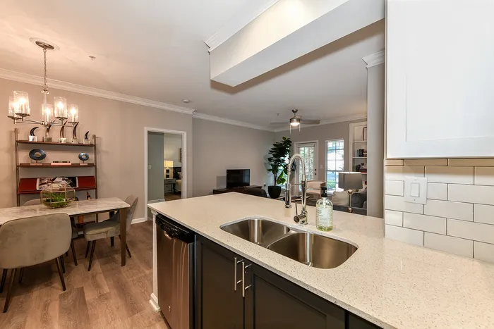 Modern open-plan kitchen and dining area featuring elegant lighting, chic furnishings, and sleek flooring.