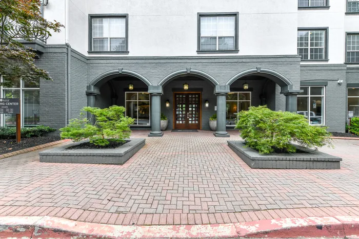 Inviting apartment entrance with elegant arches and lush greenery.