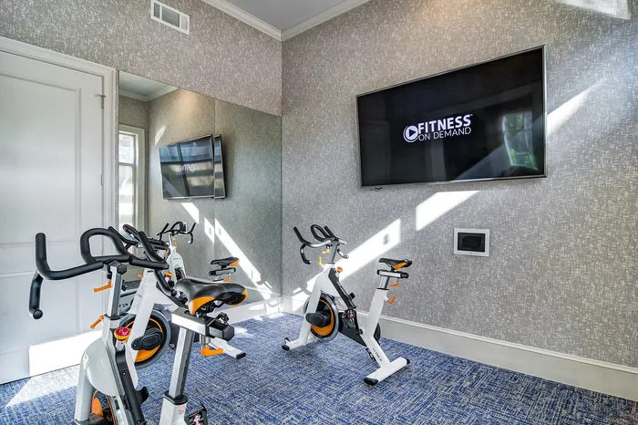 Bright and modern fitness room with high-end exercise bikes and a large screen for virtual workouts.
