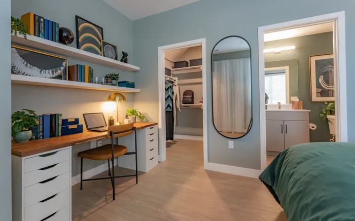 Chic home office in a cozy room featuring a modern desk with brass lamp, stylish floating shelves, and a spacious walk-in closet. Elegant design with warm lighting and contemporary decor.