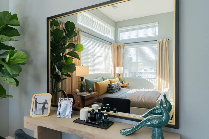 Elegantly designed bedroom with large windows, soft ambient lighting, and stylish decor reflected in a modern mirror.