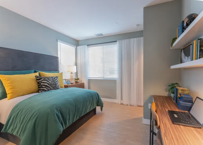 Elegant bedroom with vibrant decor, boasting large windows, a cozy desk area, and stylish shelving.