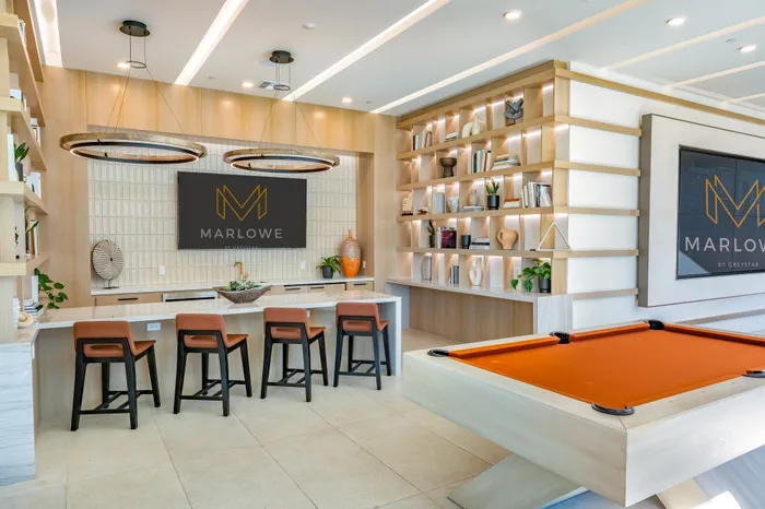 Modern lounge area with sleek bar seating, contemporary decor, and a vibrant pool table for a chic living experience.