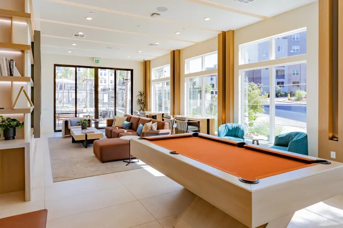 Modern and inviting lounge area with a vibrant pool table, cozy seating, large windows, and stylish decor for a perfect blend of relaxation and entertainment.