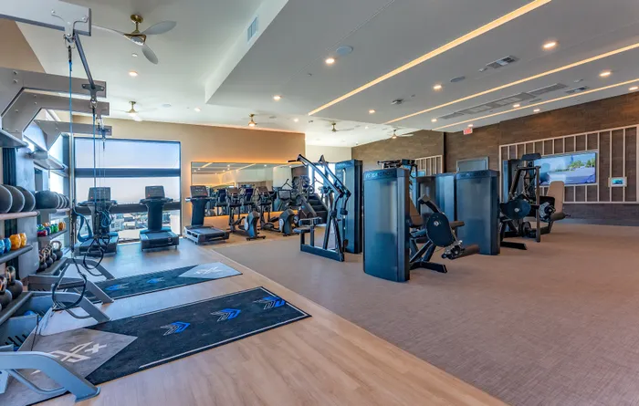 Modern fitness center with state-of-the-art equipment, featuring treadmills, weight machines, and kettlebells in a spacious, well-lit environment.