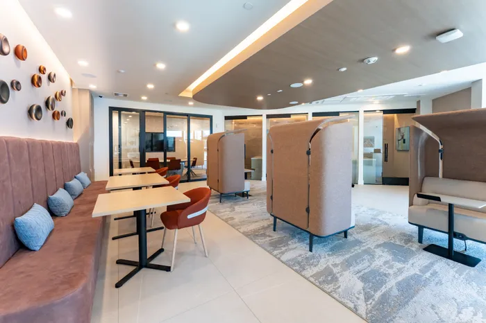 Modern and inviting co-working space with plush seating, wooden tables, and artistic wall decor, ideal for productivity and comfort.