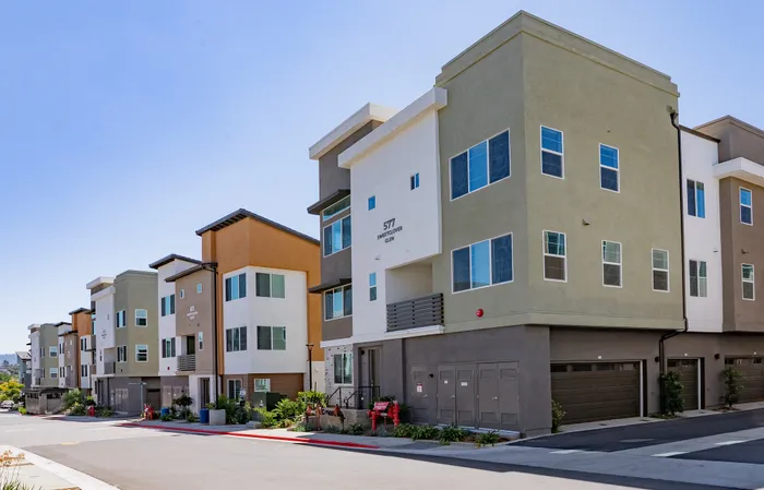 Modern townhouse community with colorful, multi-story buildings and spacious balconies, nestled in a peaceful neighborhood.