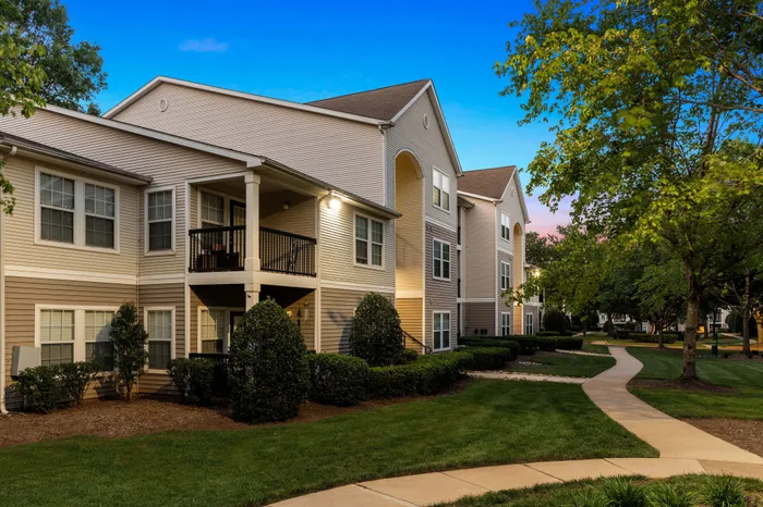 Charming apartment exterior with modern architecture set amidst lush greenery and a serene pathway.