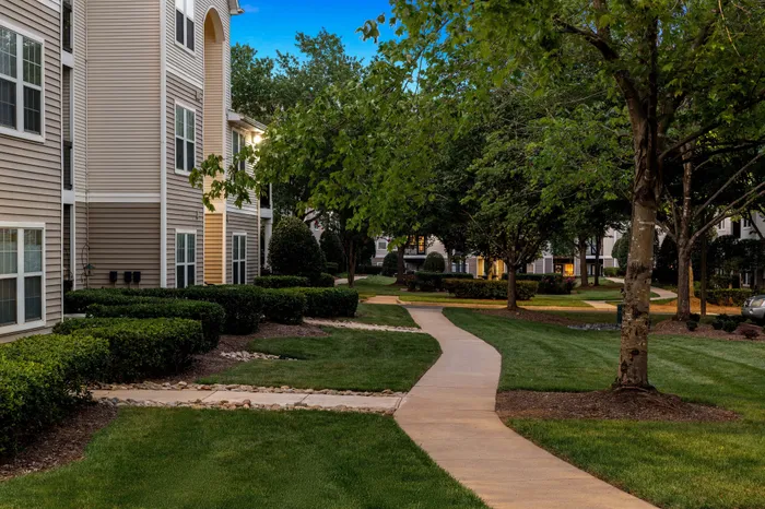 Charming apartment exterior with lush greenery and winding pathways creating a serene atmosphere.