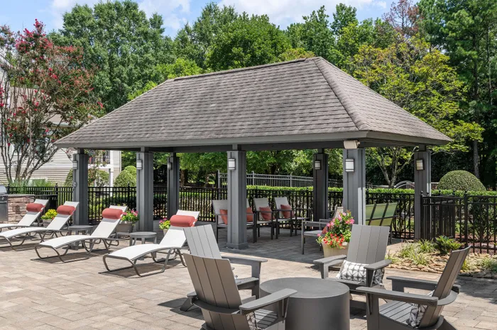 Chic outdoor patio with elegant pavilion, lounge chairs, and vibrant greenery for a tranquil retreat.