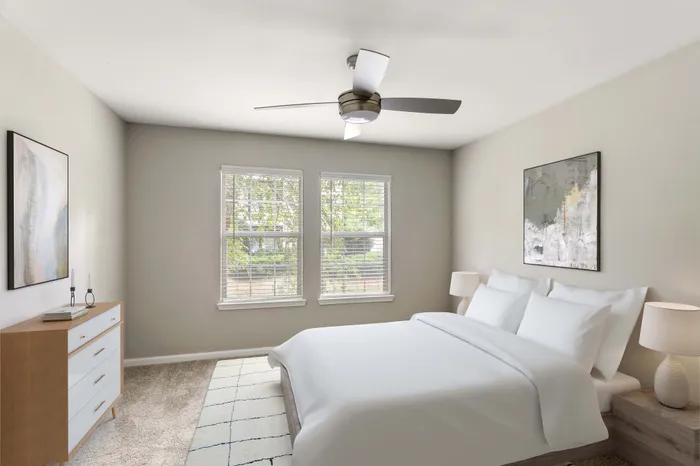 Bright and inviting bedroom with cozy carpeting, large windows, and modern ceiling fan, perfect for restful nights.