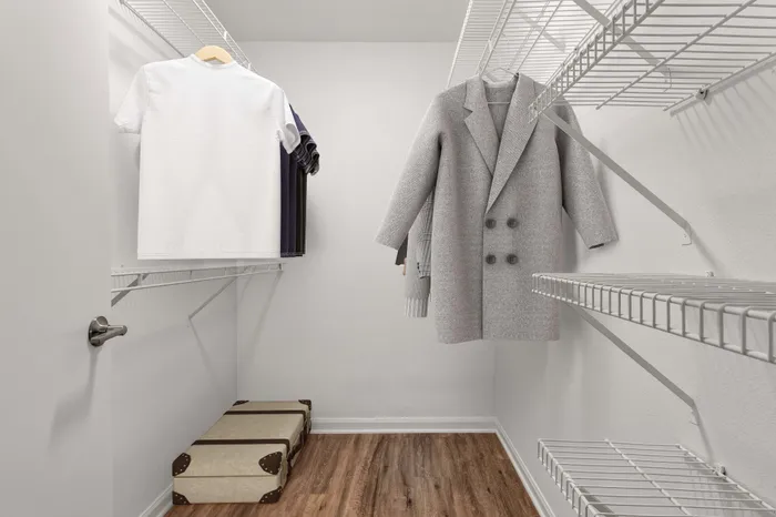 Spacious walk-in closet with stylish shelving and hanging space, featuring elegant storage solutions and crisp hardwood flooring.