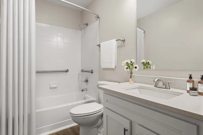 Elegant bathroom with modern fixtures, a pristine white bathtub, and a stylish vanity with fresh flowers.