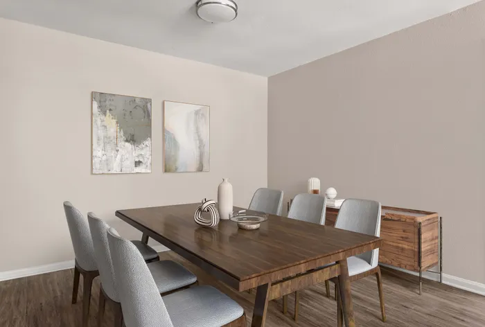 Elegant dining area featuring a sleek wooden table, six modern chairs, and contemporary art on the wall, creating a warm and inviting atmosphere.