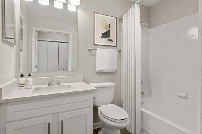 Bright, elegant bathroom featuring a pristine white bathtub, stylish countertop with modern fixtures, and chic wall art.