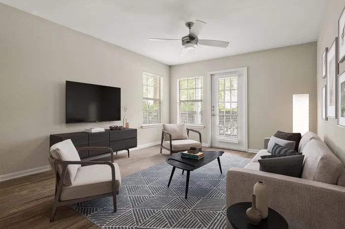 Bright and modern living room with elegant decor, featuring a sleek flat-screen TV, contemporary furniture, and large windows for natural light.