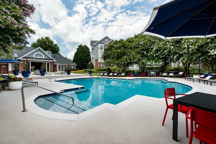 Inviting community pool area with lush greenery, modern seating, and a serene atmosphere, perfect for relaxation and socializing.