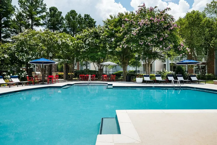 Inviting swimming pool area with elegant lounge chairs and lush landscaping, perfect for relaxation and entertainment.