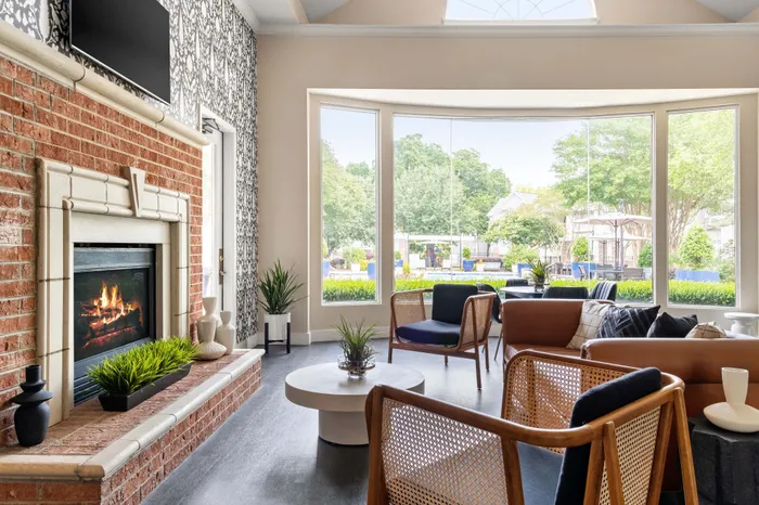 Elegant living room with a cozy fireplace, modern furniture, and large windows offering a scenic garden view.