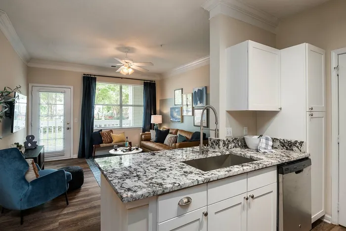 Charming open-concept living space with elegant granite countertops, cozy seating area, and large sunny windows.