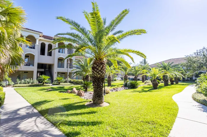 Charming apartment complex with palm-lined walkways and lush green lawns, offering a serene outdoor living experience.