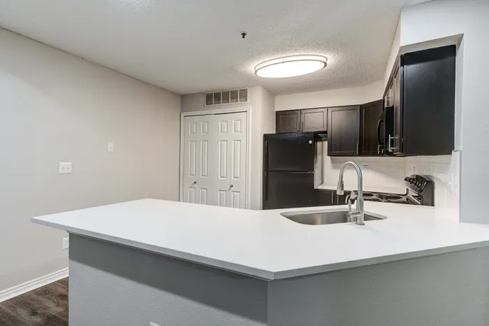 Modern kitchen with sleek black appliances, elegant dark cabinetry, and a stylish white quartz countertop island perfect for entertaining.