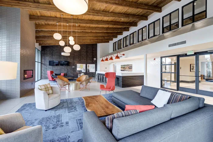 Sophisticated lounge area showcasing modern furniture, warm lighting, a cozy fireplace, and stylish decor under a vaulted wooden ceiling.