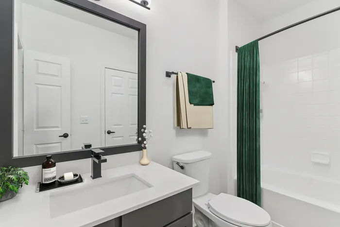 Luxurious modern bathroom with sleek fixtures, elegant green and beige towels, and a stylish vanity.