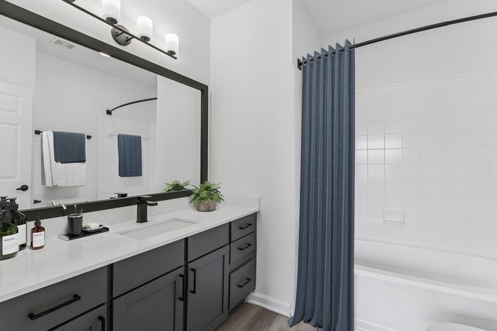 Elegant bathroom with modern fixtures, large mirror, sleek vanity, and vibrant blue shower curtain.