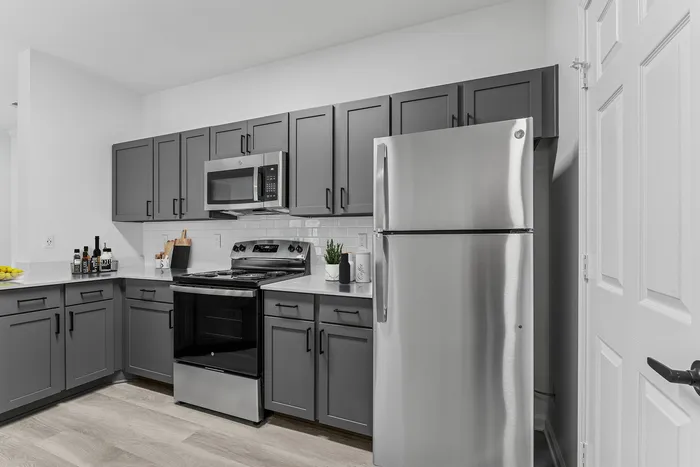 Modern kitchen with sleek grey cabinets, stainless steel appliances, and elegant white countertops.