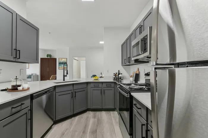 Modern kitchen with sleek gray cabinets, stainless steel appliances, and elegant countertops, featuring a spacious open-concept layout.