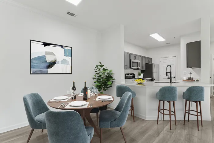 Sophisticated open-concept dining and kitchen area with elegant blue chairs, modern appliances, and chic wall art.