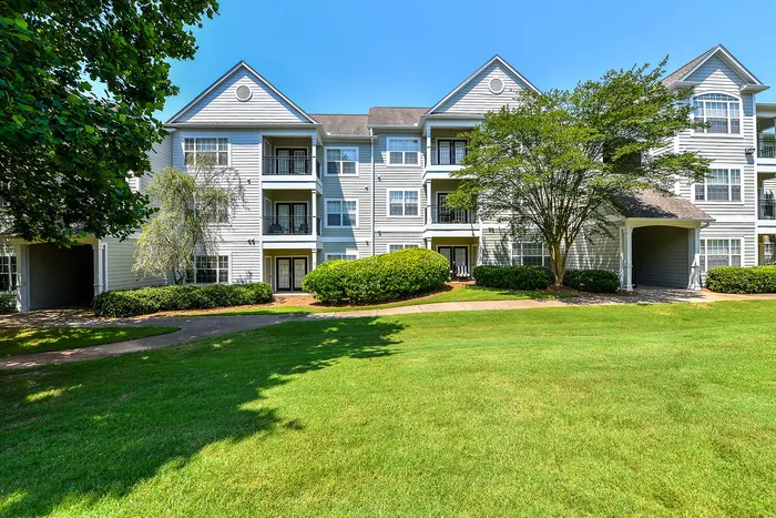 Charming multi-story apartment building surrounded by lush greenery, showcasing modern balconies and elegant exterior design.