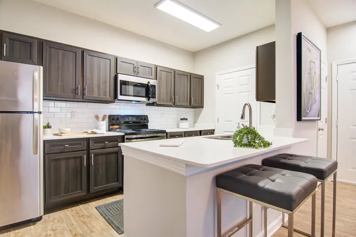 Modern kitchen with sleek dark wood cabinets, stainless steel appliances, and a chic breakfast bar complete with elegant stools.